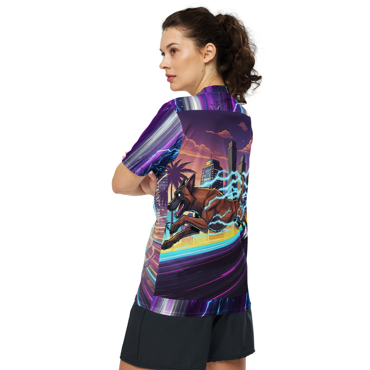 Female model showing the back of the Malinois Mayhem jersey, with a running Belgian Malinois, cyan lightning, and a sunset cityscape.