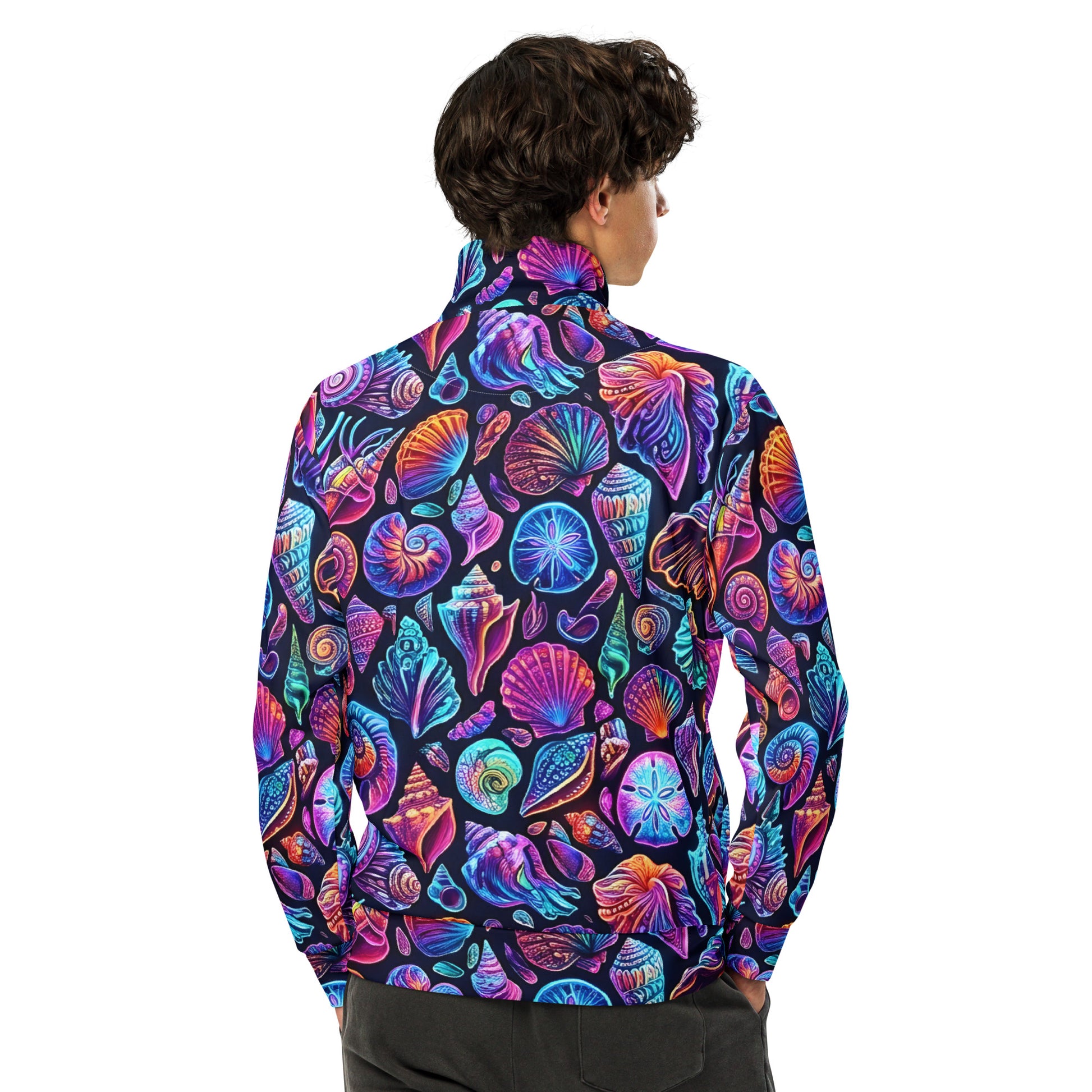 Back view of male model wearing the Chromashell Unisex Track Jacket showing the full neon seashell all-over print with spiral shells, scallops, conch, and nautilus in electric purple, teal, and pink on a dark background