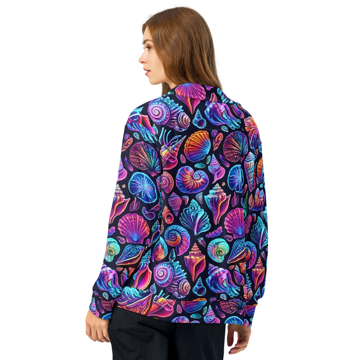Back view of female model wearing the Chromashell Unisex Track Jacket showing the full neon seashell all-over print in electric purple, pink, blue, and teal covering the back and sleeves