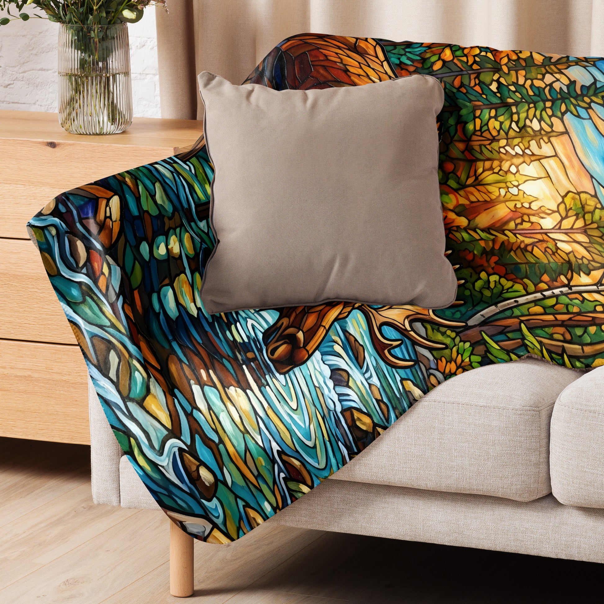 Mosaic Moose Sherpa Blanket lifestyle shot — 50x60 blanket draped over cream sofa arm with taupe throw pillow showing stained glass mosaic moose forest stream detail with cream sherpa interior visible against neutral curtain background with wood sideboard and vase of greenery