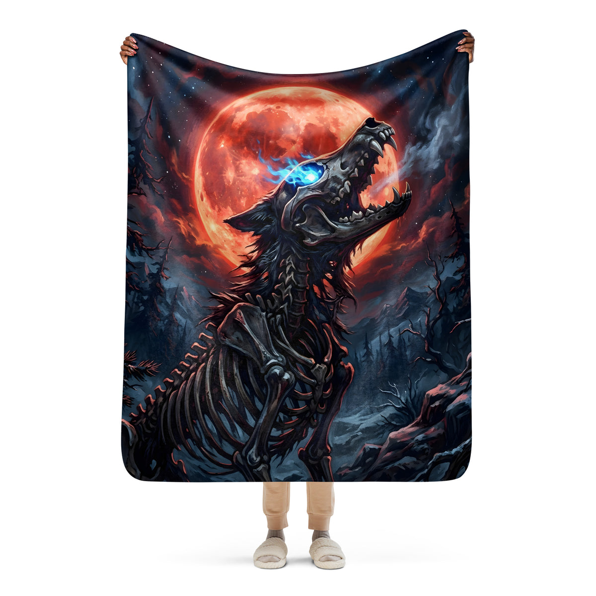 Person holding the 50 × 60-inch Blood Moon Bonewolf blanket open, displaying a skeletal wolf beneath a red moon in a shadowy forest.